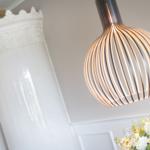 Deckenleuchte über Tisch mit Blumen und Säule