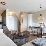 Wohn- und Essbereich mit Sofa, Tisch und Stühlen. Küche im Hintergrund.