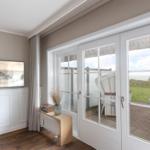 Wohnzimmer mit TV, Terrasse und Meerblick durch Glastüren.