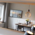 Esszimmer mit Tisch, Stühlen und Wandbild. Hängelampe und Fenster sichtbar.