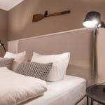 Schlafzimmer mit Bett, Kissen und Stehlampe an der Wand.