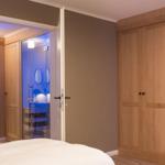 Schlafzimmer mit Blick in das Badezimmer und Holzschrank.