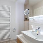 Badezimmer mit Waschbecken, Spiegel und Heizkörper