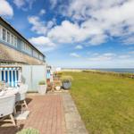 Terrasse mit Tisch, Stühlen und Blick aufs Meer.