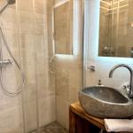 Bad mit Dusche, Steinwaschbecken und Spiegelschrank.