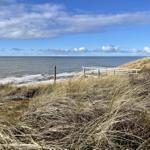 Hochgelegener Strandweg mit Blick auf das Meer und Dünen.