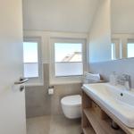 Badezimmer mit Waschbecken, Toilette und Fenstern.
