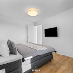 Schlafzimmer mit Bett, Fernseher und Holzboden.