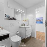 Badezimmer mit Waschmaschine, Spiegelschrank und Blick in Wohnbereich.