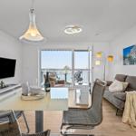 Wohn- und Essbereich mit Balkon, Sofa, Esstisch und Fernseher.