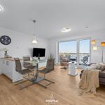 Wohn- und Essbereich mit Balkon, Sofa, Esstisch und Fernseher.