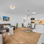 Wohn- und Küchenbereich mit Sofa, Esstisch und moderner Küche.