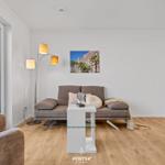Wohnzimmer mit Sofa, Tisch und Balkonansicht.