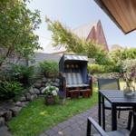 Terrasse mit Tisch, Stühlen und Strandkorb im Garten.