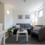 Wohnzimmer mit grauem Sofa, kleinem Tisch und Pflanzen.
