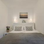 Schlafzimmer mit Bett, Nachttisch, Wandbild und Fenster.