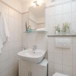 Badezimmer mit Waschbecken, Spiegel und Handtüchern an der Wand.