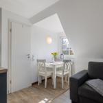 Wohnbereich mit Sofa, Esstisch und Küchenzeile unter Dachschrägen.