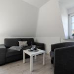 Wohnzimmer mit Sofa, Sessel und Tisch unter Dachschrägen.