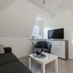 Wohnbereich mit Sofa, Fernseher und Blick in Schlafzimmer