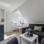 Wohnzimmer mit Sofa, Esstisch und Küche unter Dachschrägen