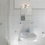 Badezimmer mit Dusche, Waschbecken und Spiegel