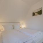Schlafzimmer mit Doppelbett, zwei Nachttischen und Wandbild.