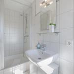 Badezimmer mit Dusche, Waschbecken und Spiegel.
