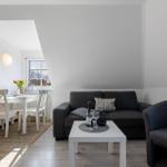 Wohnzimmer mit Sofa, Couch und Esstisch. Fenster mit Blick nach draußen.