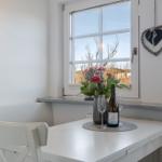 Tisch mit Blumen, Wein und Teekanne am Fenster