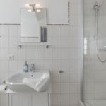 Badezimmer mit Dusche, Waschbecken und Spiegel.