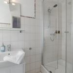 Badezimmer mit Dusche, Waschbecken und Spiegel.