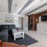 Wohnzimmer mit Ledersofa, Holztisch und Fernseher an der Wand.