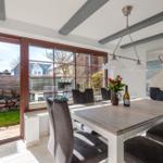 Esstisch mit Stühlen, Fenster zur Terrasse und Wandbild.
