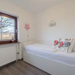 Schlafzimmer mit weißem Bett, Fenster und Wanddekoration.