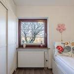 Schlafzimmer mit Bett, Fenster und Kleiderschrank.