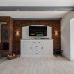 Raum mit Backsteinwand, Fernseher, Schrank und Kaminofen.