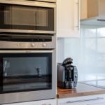 Küche mit eingebauter Mikrowelle und Backofen sowie Kaffeemaschine und Herdplatte.