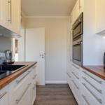 Küche mit weißen Schränken, Holzoberflächen und integriertem Backofen.