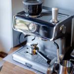 Espresso-Kaffeemaschine mit Mahlwerk und Milchkanister auf Holztisch