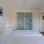 Schlafzimmer mit Doppelbett, Schrank und Wandbild.
