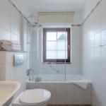 Badezimmer mit Badewanne, Dusche und Fenster. Handtuch und Seife bereit.