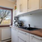 Küche mit Holzoberfläche, schwarzer Spüle und Fensterblick auf Bäume