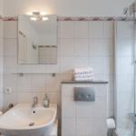 Badezimmer mit Dusche, Waschbecken und Spiegel