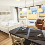 Schlafzimmer mit Bett, Tisch und Sessel. Fenster mit Jalousien und Lampe.
