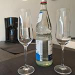 Zwei Flöten und eine Flasche Mineralwasser auf Tisch