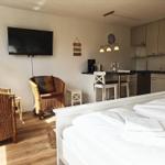 Schlafzimmer mit Bett, Sessel und Küchenbereich.