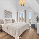Schlafzimmer mit Bett, TV und Fensterblick auf Außenbereich.