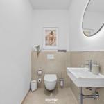 Badezimmer mit Waschbecken, Toilette und runden Spiegel