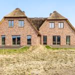 Zweistöckiges Haus mit strohgedeckten Dächern und großen Fenstern